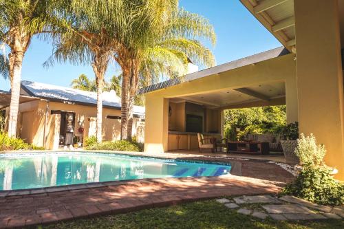 a house with a swimming pool and palm trees at Be My Guest in Upington