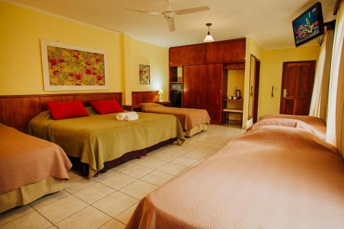 Habitación de hotel con 2 camas con almohadas rojas en Hotel Che Roga en Puerto Eldorado