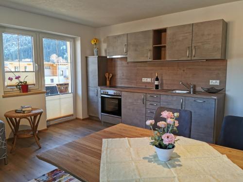 a kitchen with a table with a vase of flowers on it at Pension Tannheim in Tannheim