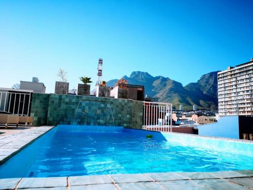 a swimming pool on the roof of a building with mountains at Urban Oasis Aparthotel in Cape Town