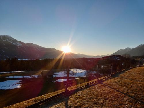 a sun setting over the mountains with a fence at Haus Tilia Karinthië Appartementen in Nötsch