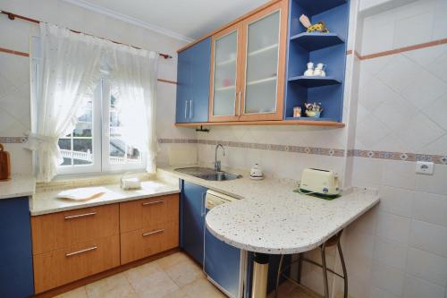 a small kitchen with blue cabinets and a sink at Apartamento Ama in Isla