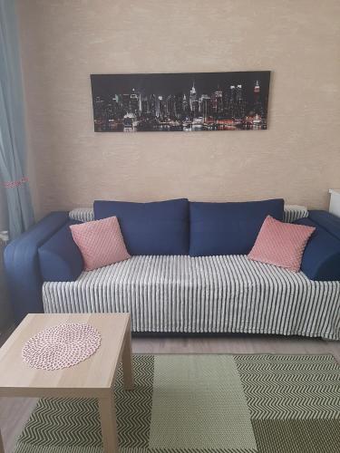 a living room with a blue couch with pink pillows at Garsoniera Kościuszki in Jasło