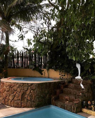 a swimming pool with a bird sculpture hanging from a tree at Pousada Miramar in Marataizes