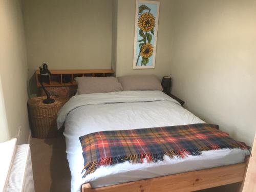 um quarto com uma cama com um cobertor xadrez em Cynfaen house em Corwen