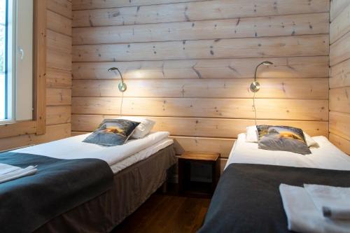 two beds in a room with wooden walls at Kolin Lotus Superior in Kolinkylä