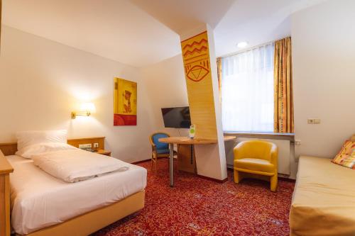a hotel room with two beds and a desk at ALLVITALIS Traumhotel in Karlsruhe