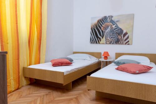 2 camas en una habitación con una foto de cebra en la pared en Apartman Duce Milka, en Duće