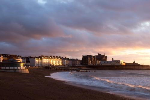 a beach with buildings and the ocean at sunset at Plas Dolau Country Estate in Aberystwyth