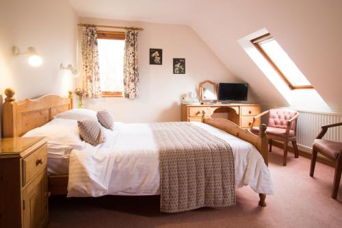a bedroom with two beds and a tv and a chair at Plas Dolau Country Estate in Aberystwyth