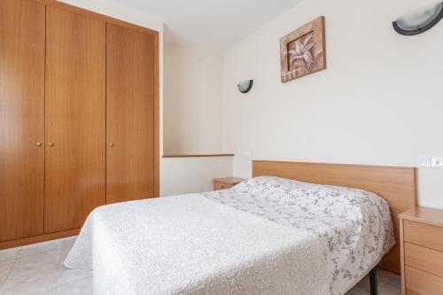 - une chambre avec un lit et une armoire en bois dans l'établissement Passeig del Mar, à L'Escala