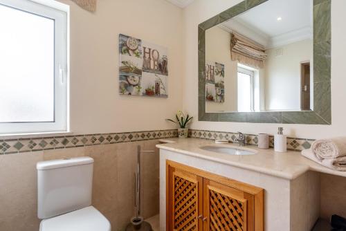 a bathroom with a toilet and a sink and a mirror at Luxury two bedroom Palheiro Village by HR Madeira in São Gonçalo