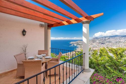a patio with a table and chairs on a balcony at Luxury two bedroom Palheiro Village by Holiday Rental Madeira in Funchal