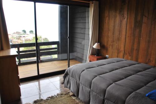 a bedroom with a large bed and a large window at Lodge Casa Vieja in Curanipe