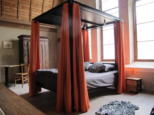 1 dormitorio con cama con dosel y cortinas de color naranja en La chapelle de Melin, en Auxey-Duresses