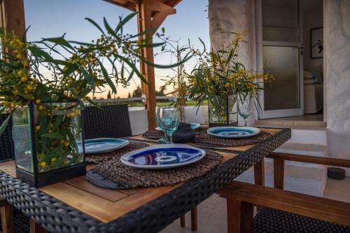 een houten tafel met borden en glazen erop bij Akamas Sunset Bohemian Chic Apartment by ONE VILLAS in Polis Chrysochous