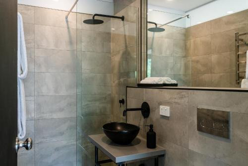 a bathroom with a glass shower with a bowl on a table at Castlemaine Gardens Luxury Glamtainer in Castlemaine