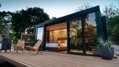 Zimmer mit einem Bett und zwei Stühlen auf einer Holzterrasse in der Unterkunft Castlemaine Gardens Luxury Glamtainer in Castlemaine