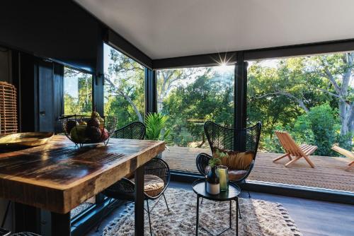 Cette chambre dispose d'une grande fenêtre et d'une table avec des chaises. dans l'établissement Castlemaine Gardens Luxury Glamtainer, à Castlemaine