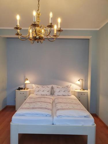 um quarto com uma cama branca e um lustre em Hotel Sophien-Café em Leer
