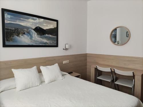 a hotel room with a bed and a picture on the wall at Pensi&oacute;n Atxiki in San Sebasti&aacute;n