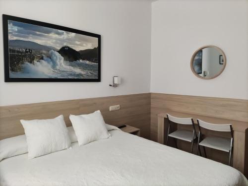 una camera d'albergo con un letto e una foto appesa alla parete di Pensión Atxiki a San Sebastián
