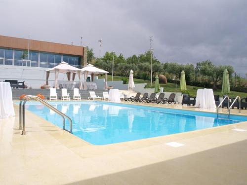 a large swimming pool with chairs and umbrellas at Hotel Estalagem Turismo in Bragança