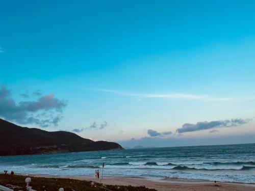 a beach with people standing on the sand and the ocean at The View Hotel in Cam Lâm