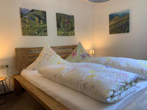 een slaapkamer met 2 bedden en schilderijen aan de muur bij Alpseeperle in Bühl am Alpsee