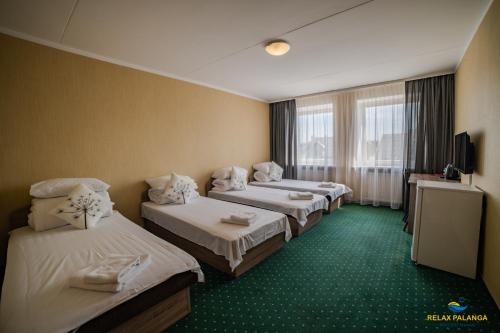 a hotel room with three beds and a television at Guest House RELAX PALANGA in Palanga