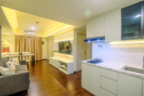 a kitchen and living room with a couch and a table at New Furnished and Minimalist 3BR at Meikarta Apartment By Travelio in Cikarang