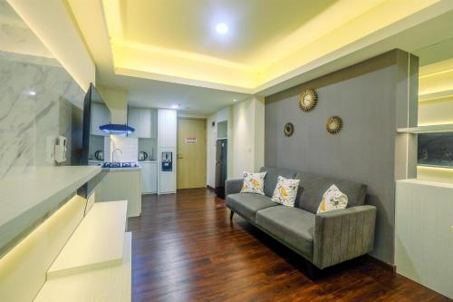 a living room with a couch and a kitchen at New Furnished and Minimalist 3BR at Meikarta Apartment By Travelio in Cikarang