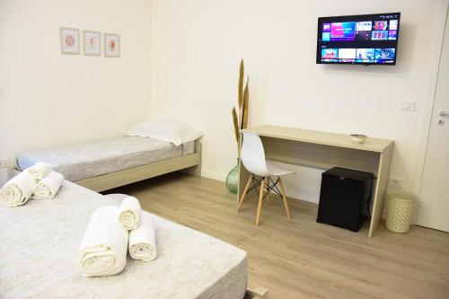 a room with two beds and a desk and a tv at Accòmodati - Camere e Appartamenti in Marina di Gioiosa Ionica