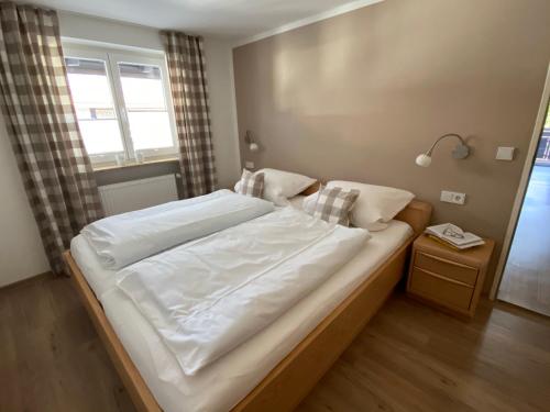 a bedroom with a large bed with white sheets at Ferienwohnungen im Färberhaus in Fischen