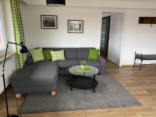 a living room with a gray couch and a table at Ferienwohnungen im Färberhaus in Fischen