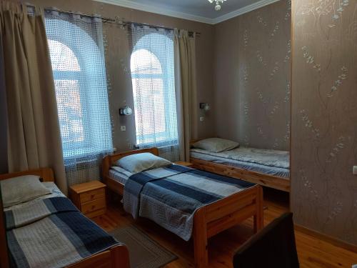 two beds in a room with two windows at Готель "Монастирський" in Putyvlʼ