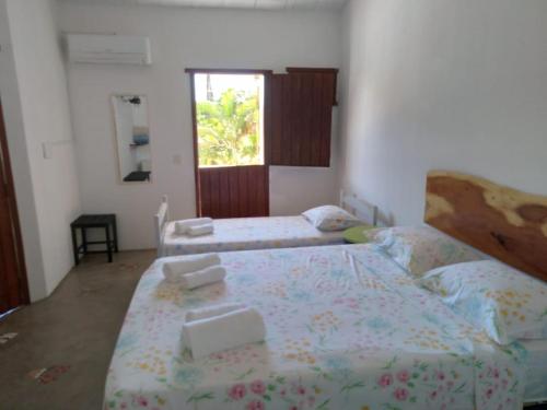 um quarto com 2 camas e uma janela em Pousada garça real em Itaúnas