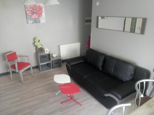 sala de estar con sofá negro y sillas rojas en GM, en Bagnères-de-Bigorre