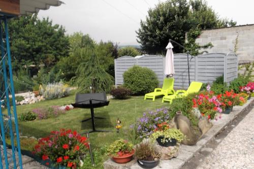 un jardín con mesa, sillas y flores en GM, en Bagnères-de-Bigorre