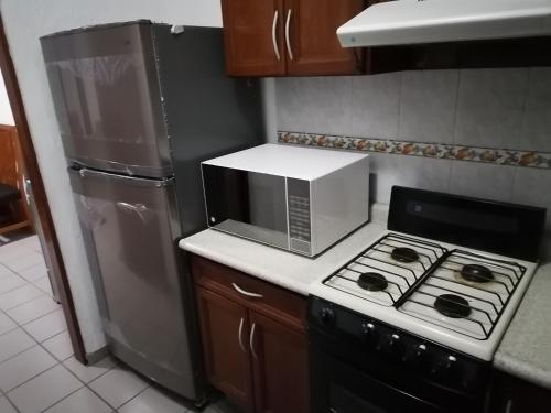 a kitchen with a microwave on top of a stove at Bonita casa amueblada para 12 personas a 3 Kms del centro Cuernavaca in Cuernavaca