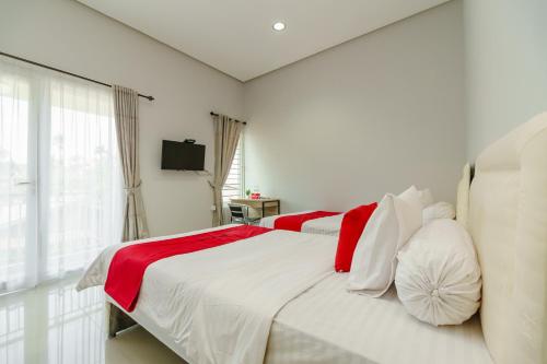 Un dormitorio blanco con una cama grande con almohadas rojas y blancas en RedDoorz @ Jalan Demang Lebar Raya Palembang, en Palembang