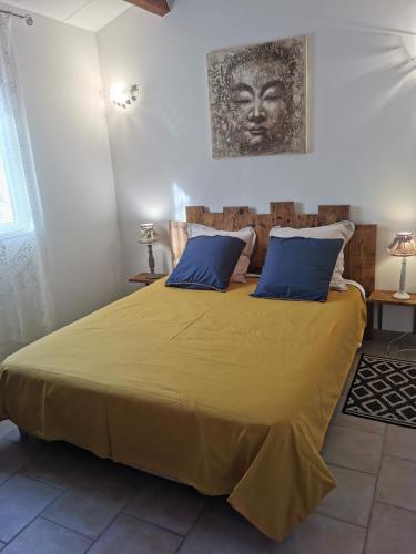um quarto com uma grande cama amarela com almofadas azuis em le petit st Jean em Cazouls-d Herault