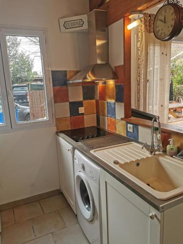 une cuisine avec une machine à laver et un évier dans l'établissement le petit st Jean, à Cazouls-d Herault