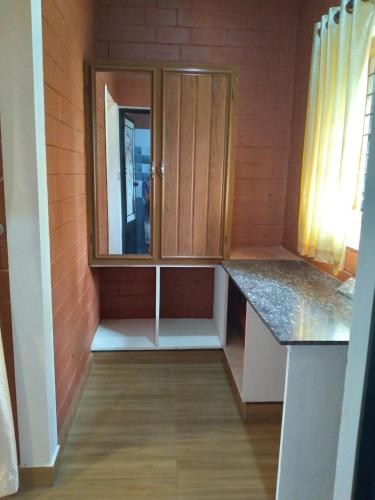 uma pequena cozinha com armários de madeira num quarto em Tranquil Farms em Manimala