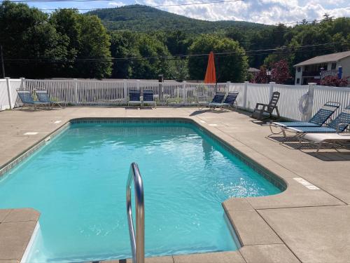 a large swimming pool with chairs and a fence at Hillside Motel in Lake George