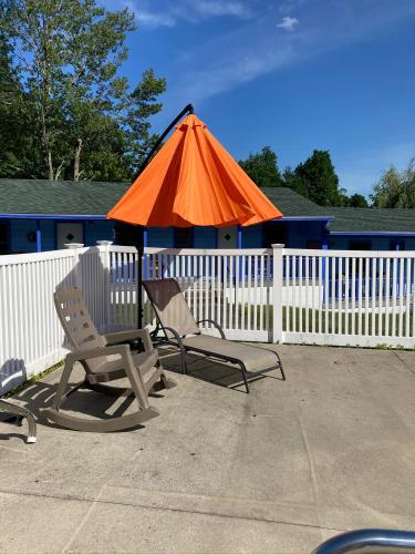 two chairs and an orange umbrella next to a fence at Hillside Motel in Lake George