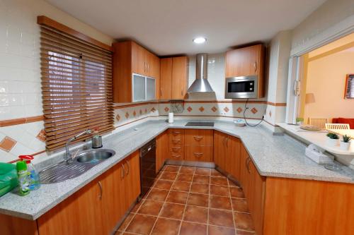 a large kitchen with wooden cabinets and a sink at At the center & very close to the Paseo beach, with double garage, renovated and fully equipped apartment in Almuñécar