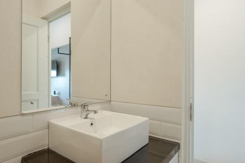 La salle de bains blanche est pourvue d'un lavabo et d'un miroir. dans l'établissement RedDoorz Syariah Plus @ BSD City, à Cilalung
