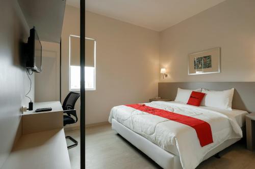 a bedroom with a large bed with a red blanket at RedDoorz Syariah Plus @ BSD City in Cilalung