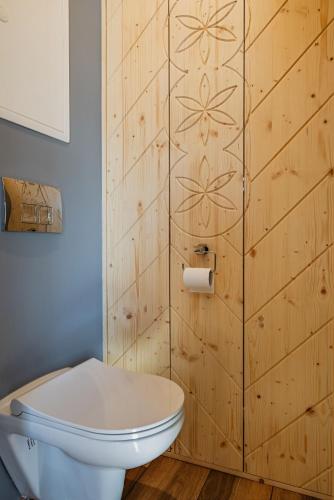 a bathroom with a toilet and a wooden wall at Noclegi domek in Kościelisko